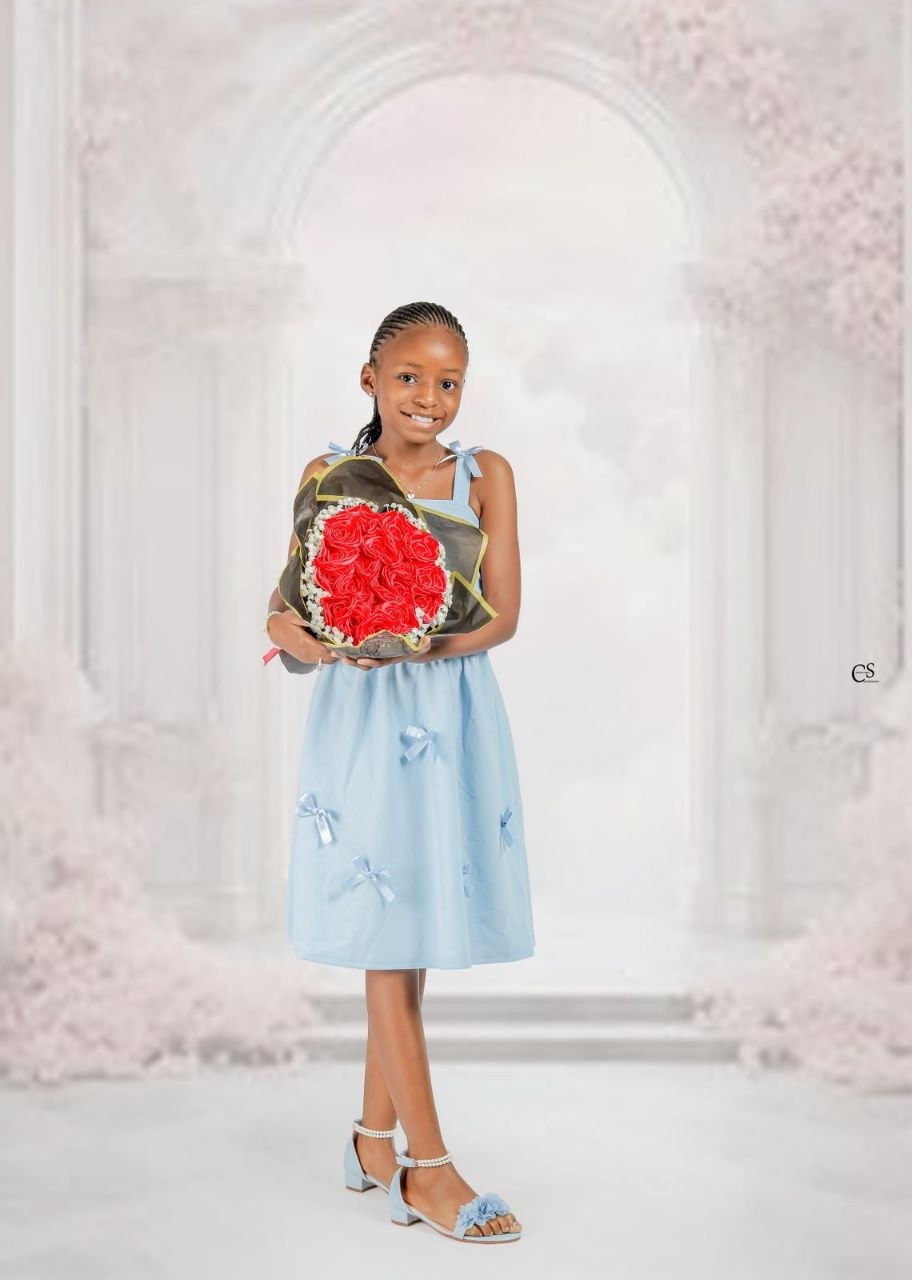 Young girl in a blue dress holding red roses