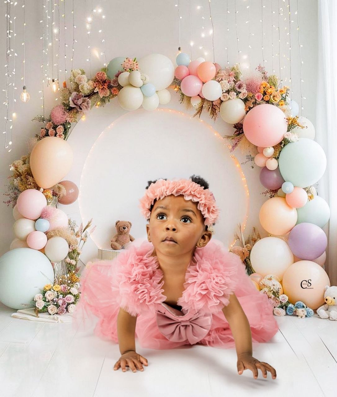 Baby girl in a pink dress at a floral balloon circle