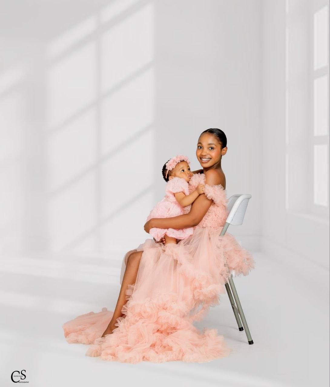 Mother holding her baby girl in matching pink dresses