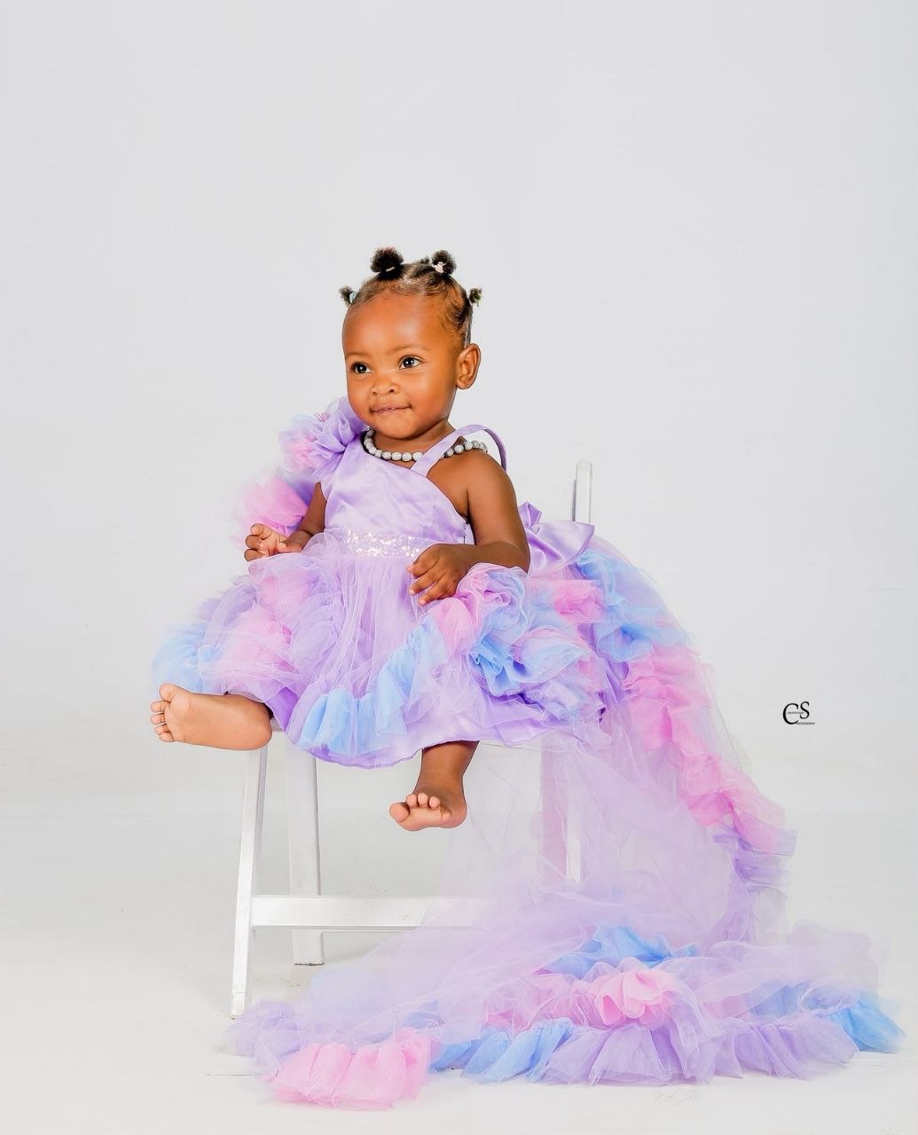 Baby girl seated in a purple and pink dress