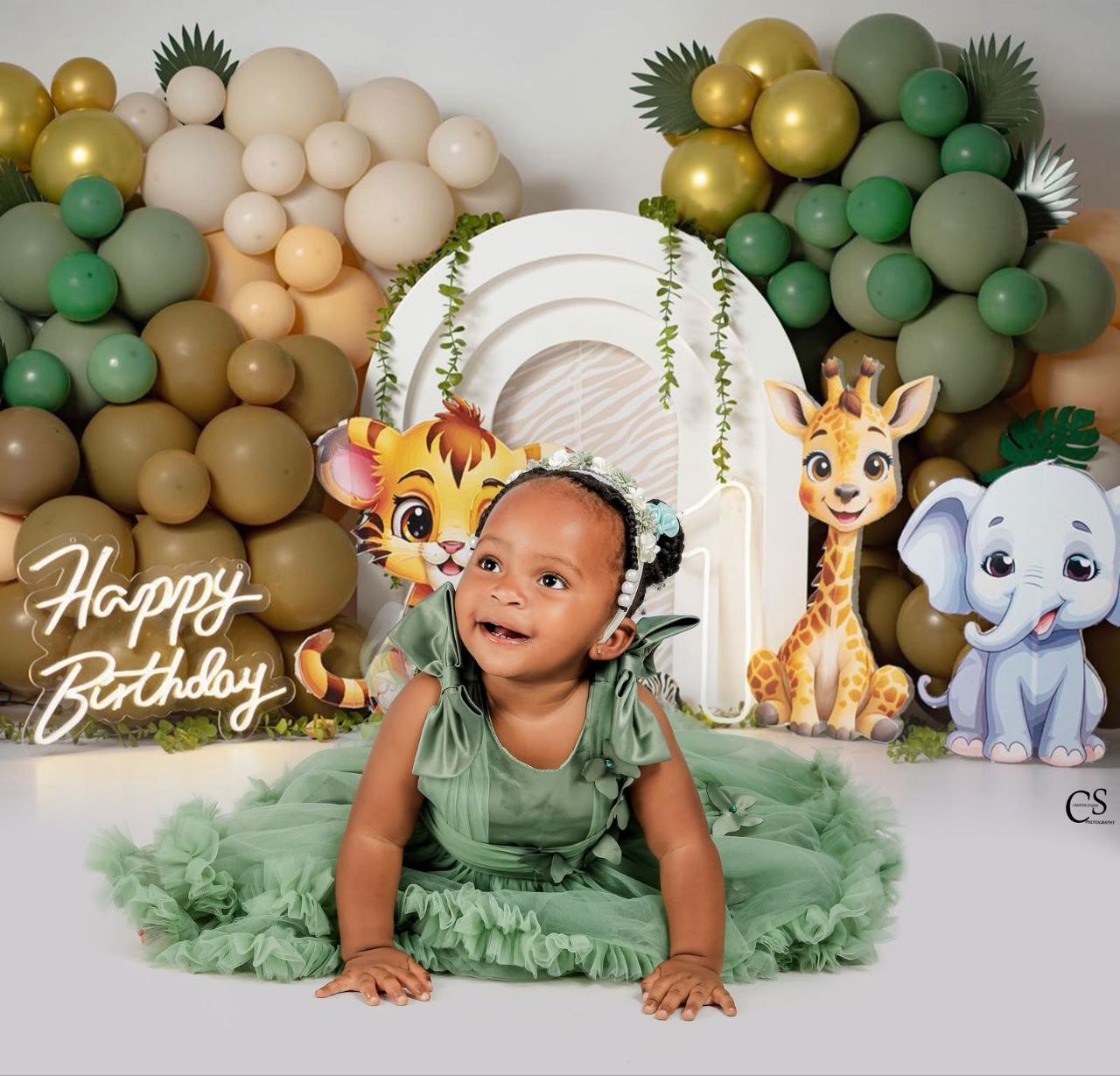 Baby girl in a green dress at a safari birthday set